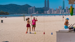 A beach with people, a city skyline, and a tent. - HANNA Balneário Hotel (Balneário Camboriú)