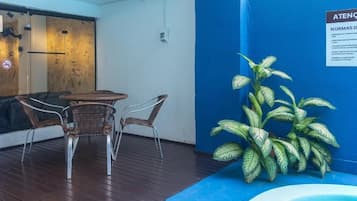 Un patio con sillas de mimbre, una mesa redonda pequeña y una planta en maceta.