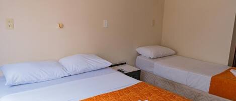A hotel room with two single beds, a nightstand, and a wall socket.