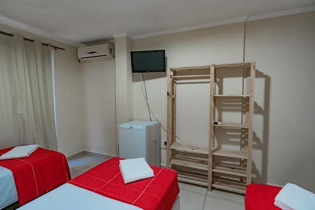 Ein Hotelzimmer mit zwei Betten, einem Fernseher, einer Klimaanlage und einem Holzschrank.