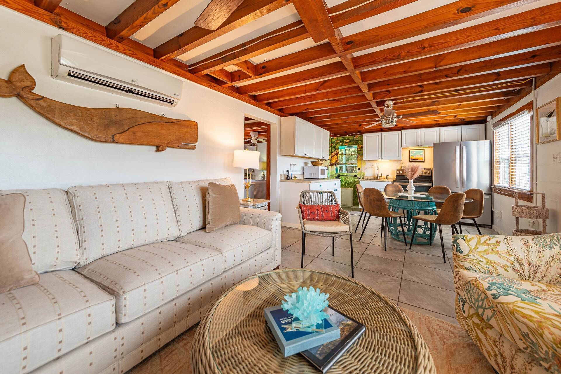 A cozy living room with a sofa, a coffee table with a book, and a dining area with chairs and a table.