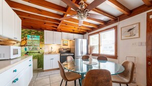 A kitchen with white cabinets, a glass dining table, and a ceiling fan. - Oh So Sandy! - Southern Shores, Historic Flat Top, 100 Yds to Beach, Pets OK, Flex Stays (Southern Shores)