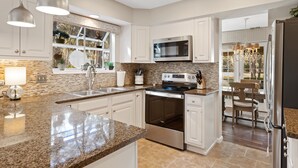 A modern kitchen with granite countertops, stainless steel appliances, and white cabinetry.