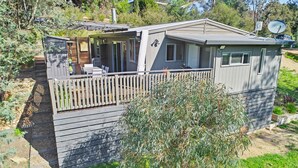Une maison mobile dotée d’une terrasse clôturée, d’une antenne parabolique et d’un petit jardin.