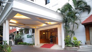 Ein Hotel Eingang mit überdachter Veranda, einer roten Teppich лестницы und einem Wachmann.