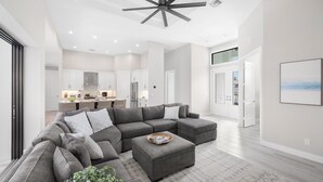 Un salon moderne avec un canapé d’angle, une table basse et un ventilateur de plafond.