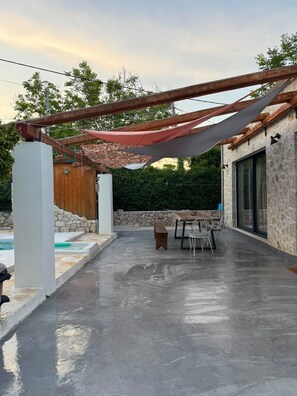 A covered outdoor patio with a pool, stone walls, and a table with chairs. - Villa With Pool in Pelekas Near the Beach (Corfu)