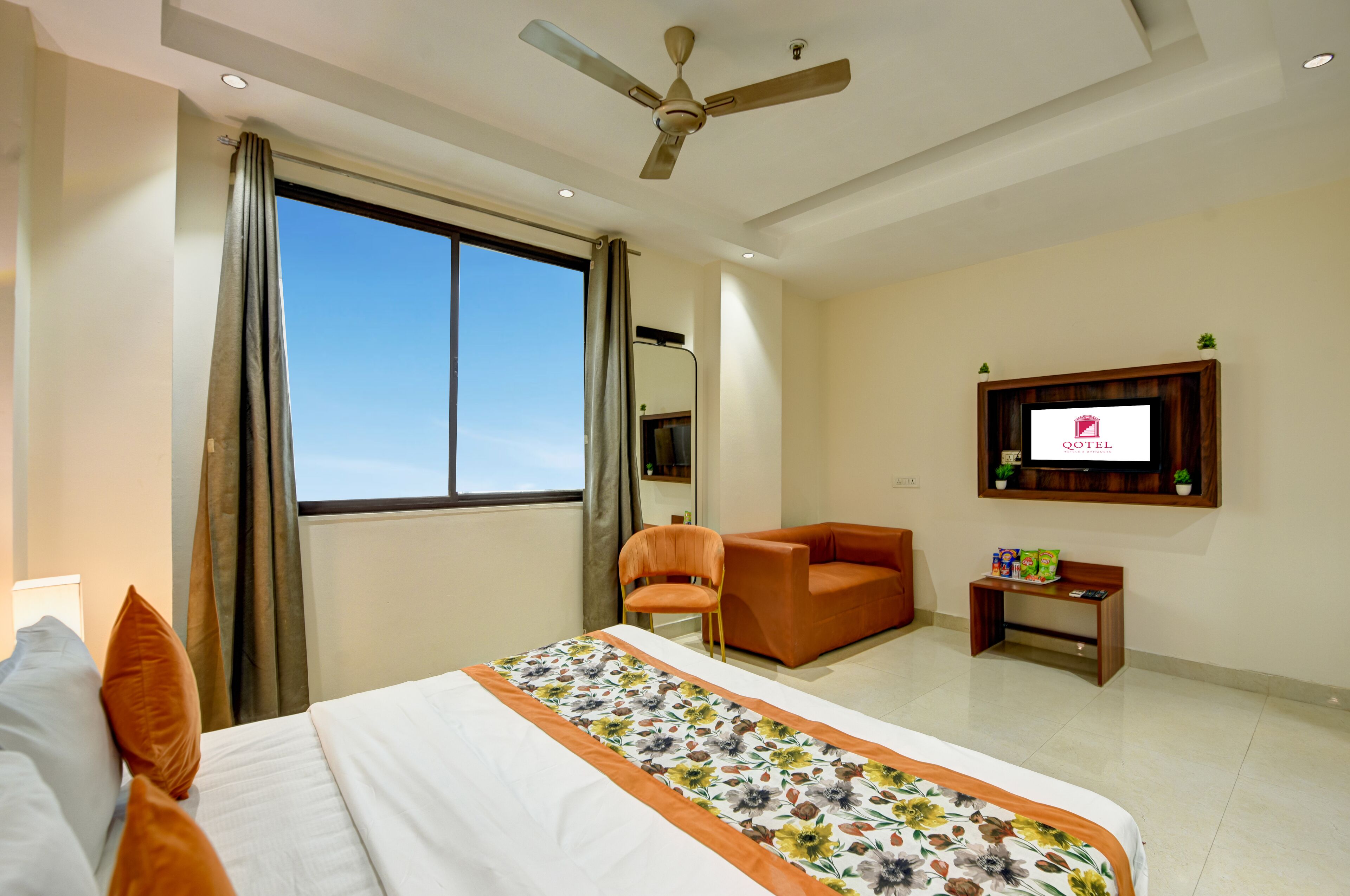 Una habitación de hotel con cama, una silla, un televisor y una ventana.
