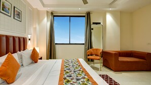 Habitación de hotel con cama, una silla, un sofá, ventilador de techo y ventana con cortinas.