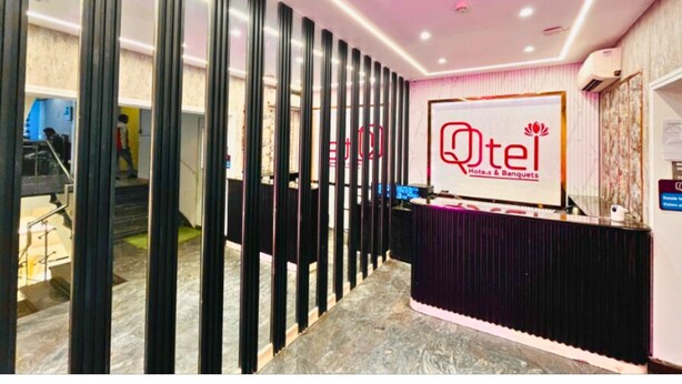 Un área de recepción de diseño moderno, con un mostrador de recepción y un cartel que dice "Qtel Hotels & Banquets".