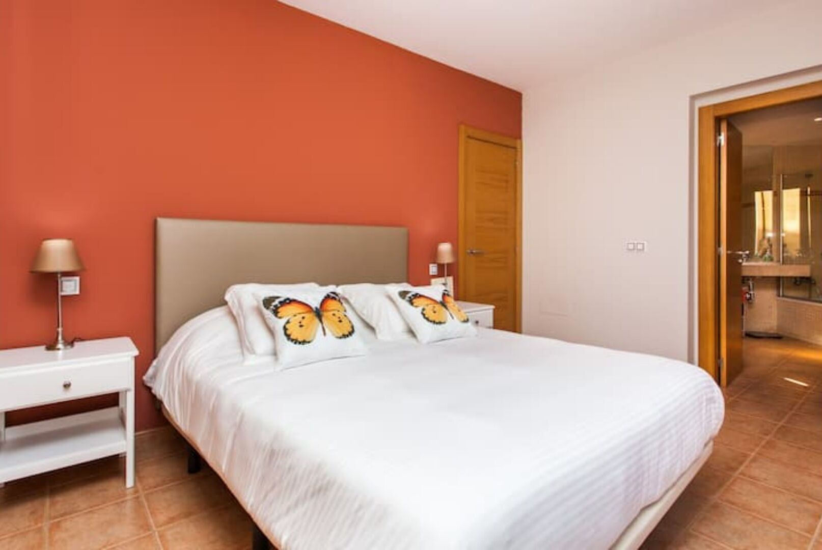 Une chambre d’hôtel avec un grand lit, deux tables de chevet et une porte donnant sur une salle de bain.