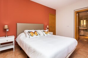 A hotel room with a large bed, two bedside tables, and a door leading to a bathroom. - Villa Sabine con Piscina, Vista Campo Golf y mar (Antigua)