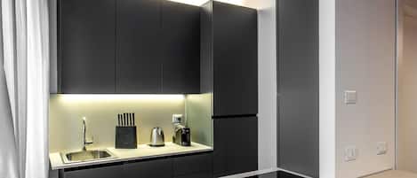 Una cocina moderna con armarios oscuros, una encimera blanca y una estufa empotrada.