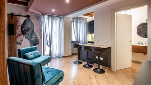 En moderne stue med en sofa, et spiseområde med bar, og et køkken, der ses igennem en åben dør.