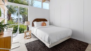 A bedroom with a bed, bedside table, lamp, and large windows. - Racquet Club Rendezvous – Palm Springs Escape (Palm Springs)