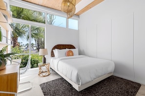 A bedroom with a bed, bedside table, lamp, and large windows. - Racquet Club Rendezvous – Palm Springs Escape (Palm Springs)