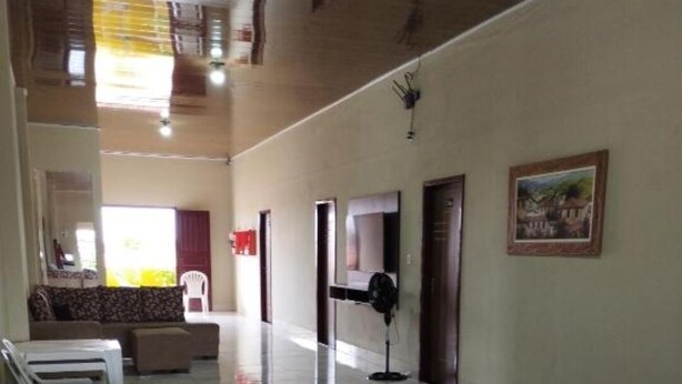 A hotel lobby with a marble floor, sofas, a fan, and a painting on the wall. - Pousada Terra Bela (Buriticupu)