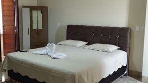 A bedroom with a large bed, a wardrobe, and a mirror. - Pousada Terra Bela (Buriticupu)