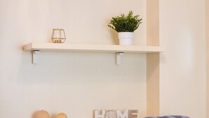 A bedroom with a bed, a pillow, a shelf with decorative items, and a wall-mounted sign that reads "HOME". - Céntrico Apartamento en Santa Cruz (Santa Cruz de Tenerife)