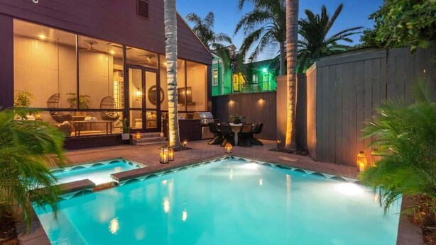 Ein modernes Haus mit Swimmingpool, Sitzgelegenheiten im Freien und einer gut beleuchteten Terrasse.