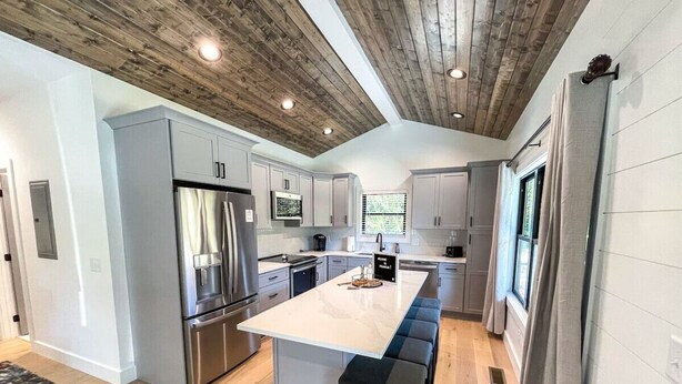 Una cucina moderna con isola centrale, elettrodomestici in acciaio inossidabile e soffitto in legno.