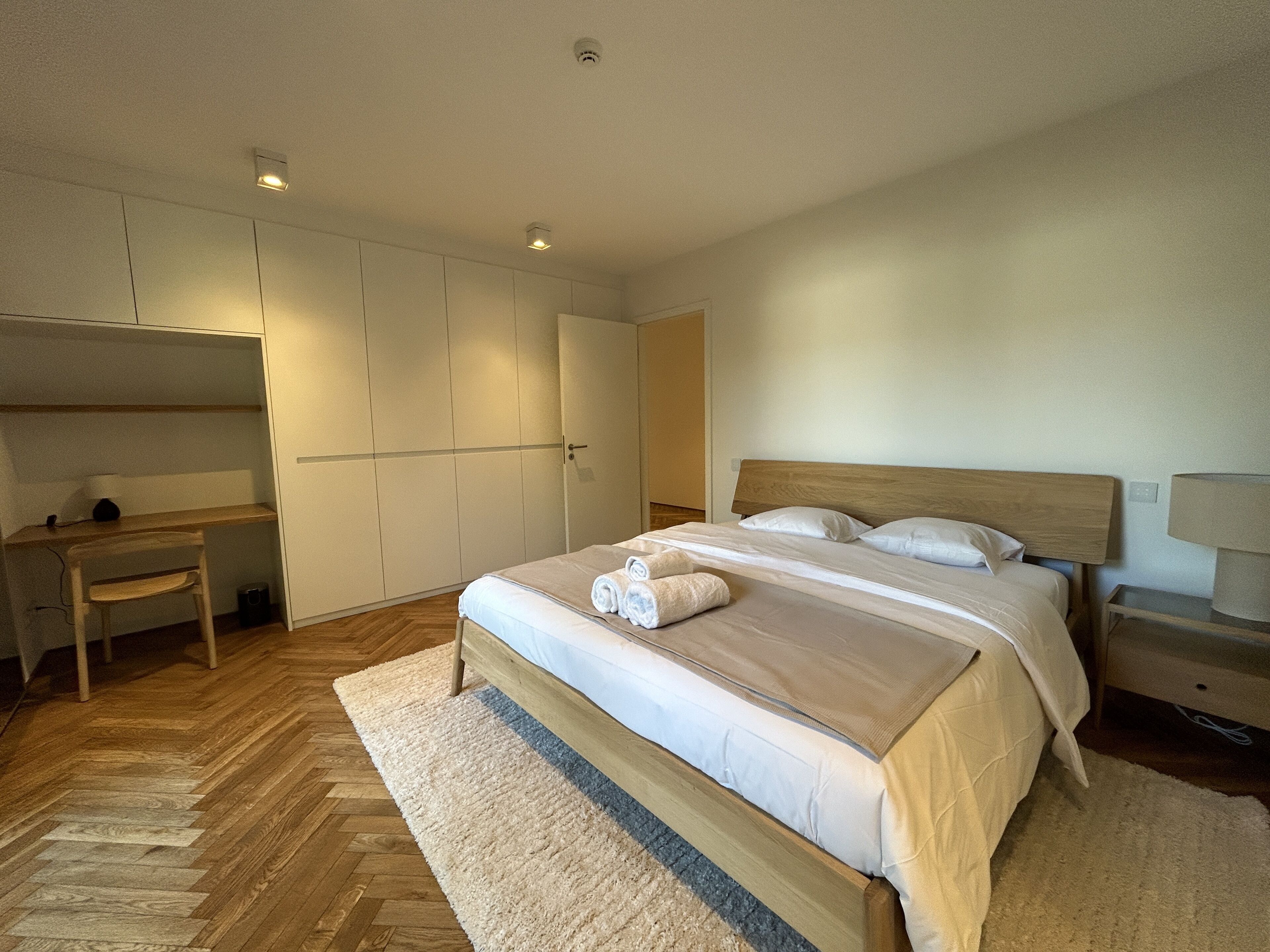 Un dormitorio con cama, escritorio y armario.