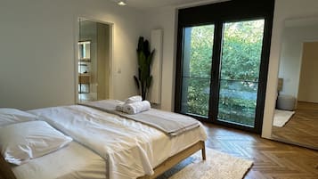 Ein modernes Schlafzimmer mit einem großen Bett, einer Schiebetür zum Balkon und einem Spiegel.