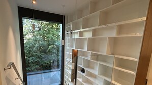 Een modern interieur met een glazen deur naar een balkon, een inbouw wit schapenkast en houten vloeren.