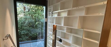 Ein modernes Interieur mit einer Glastür, die auf einen Balkon führt, einer weißen, eingebauten Regaleinheit und Holzböden.