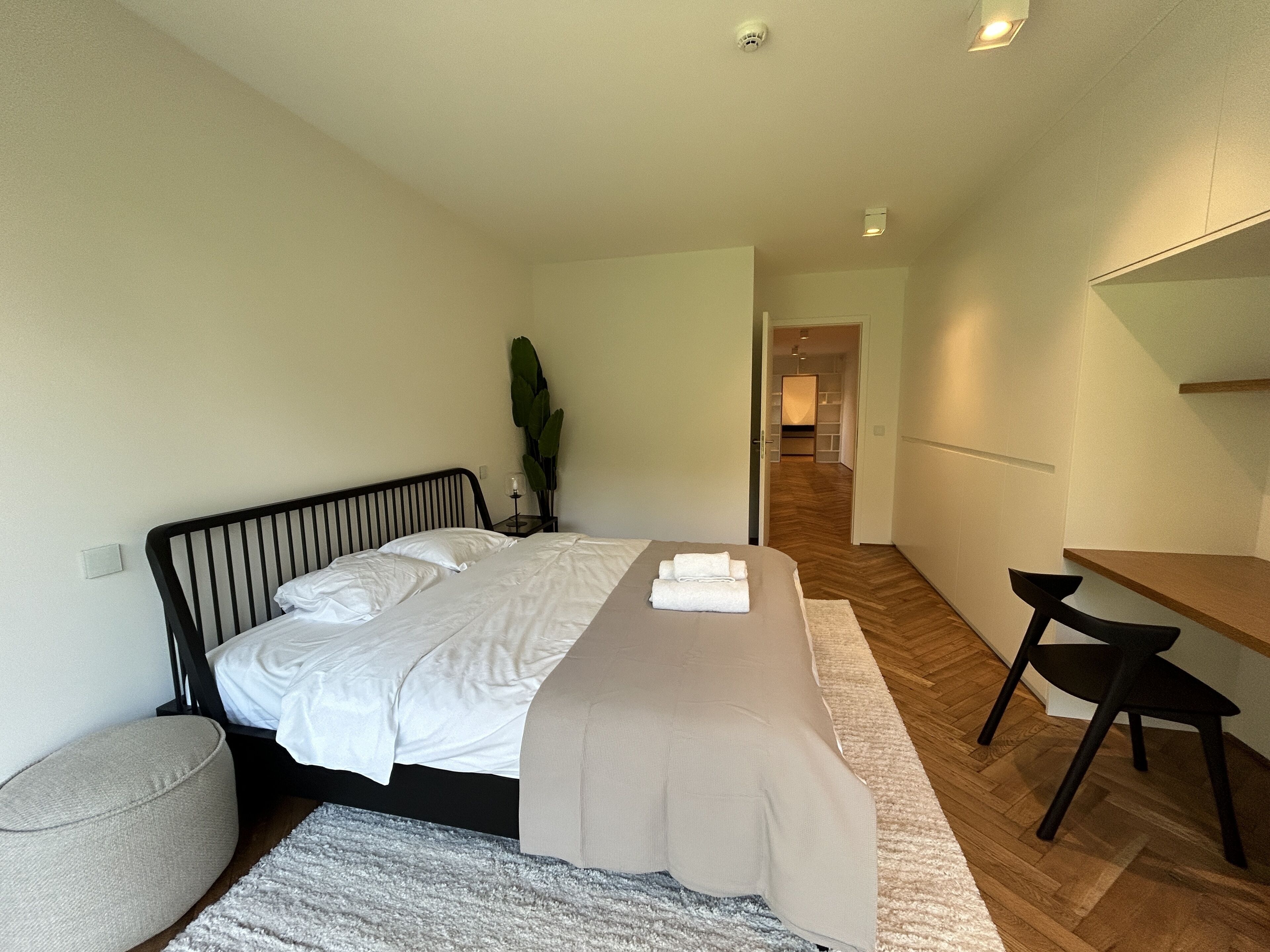 A modern bedroom with a bed, bedside table, and a desk.