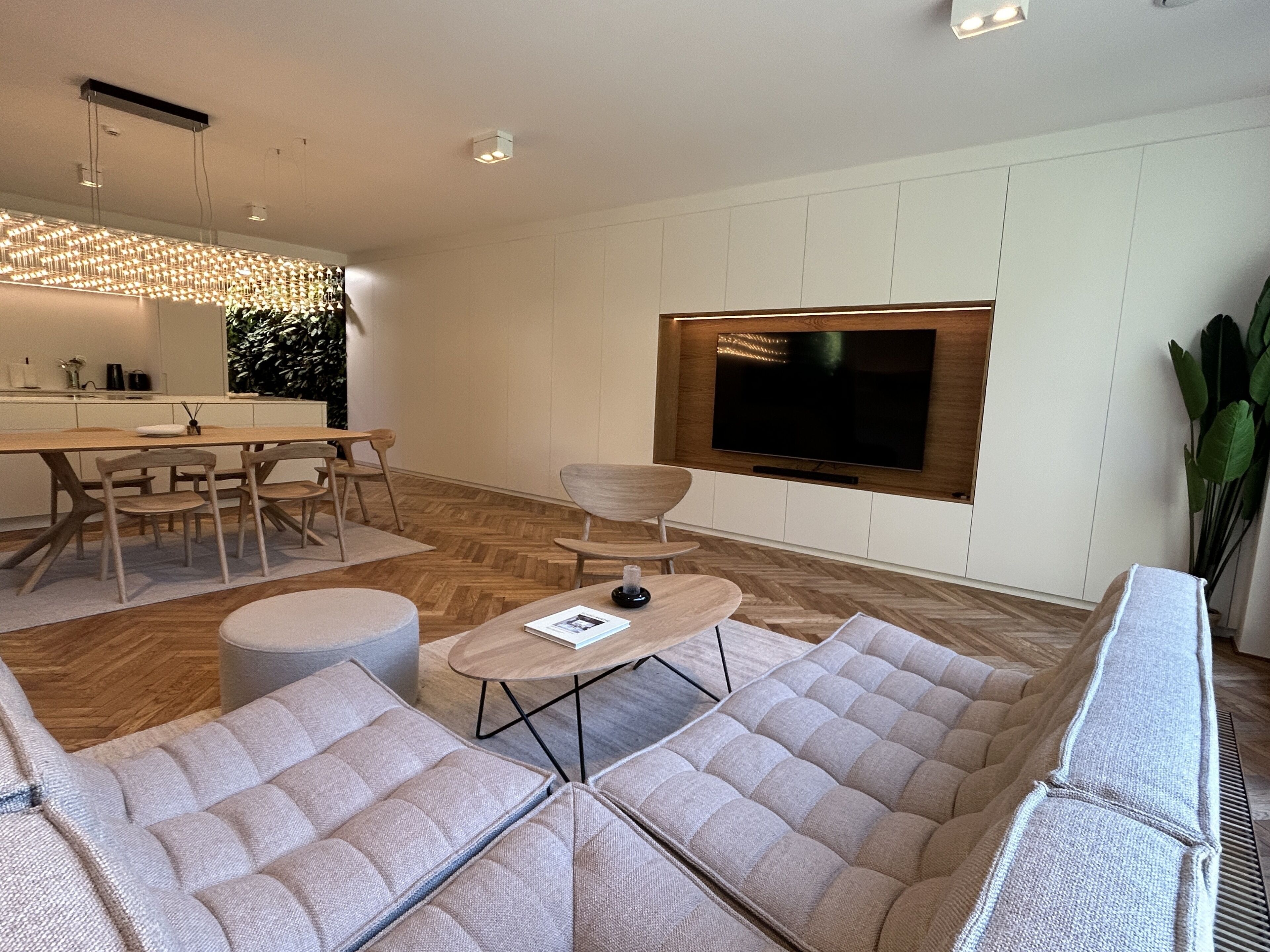 Un salon moderne doté d’un grand téléviseur, de sièges confortables et d’un coin repas.