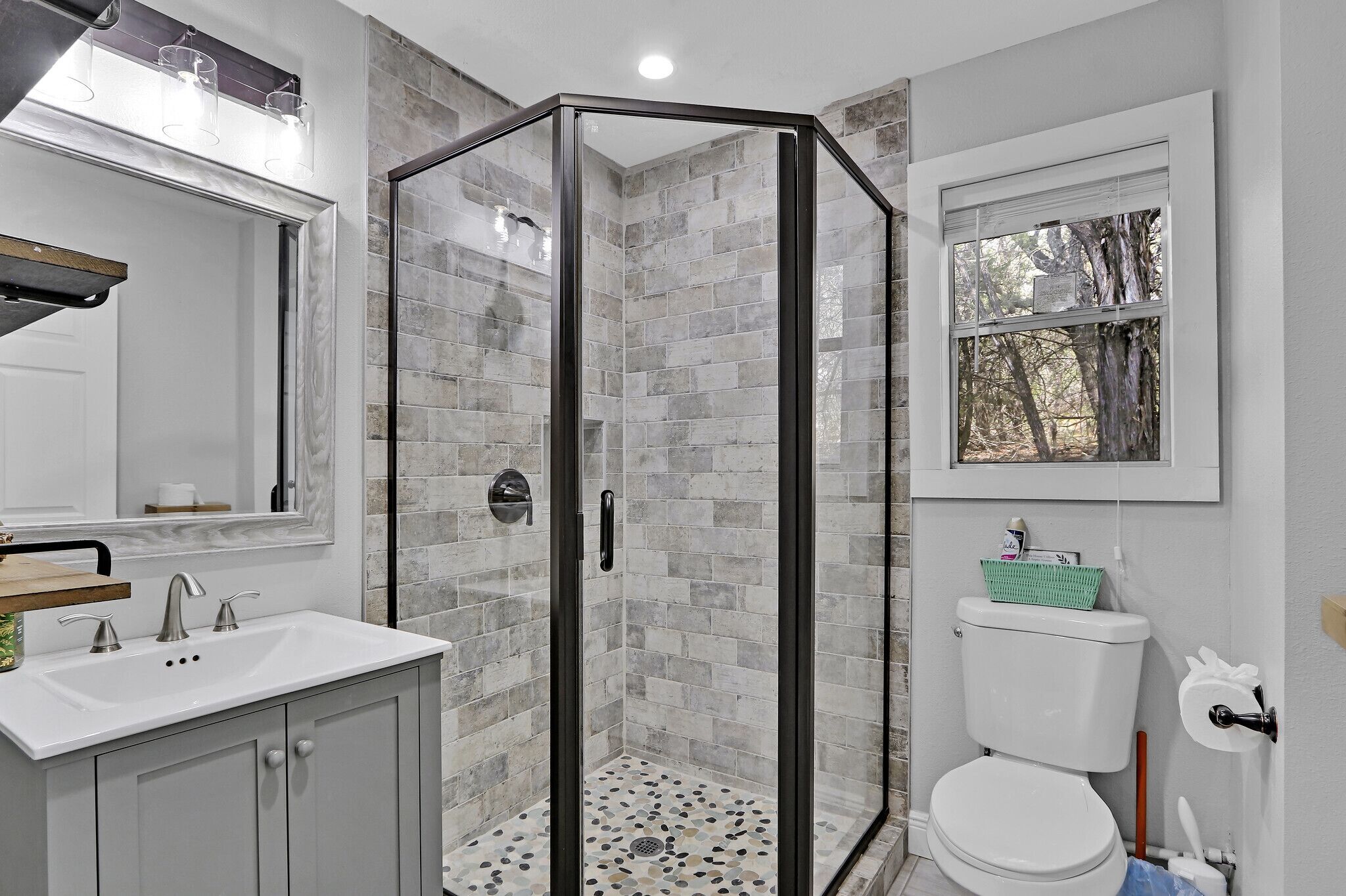 A bathroom with a glass-enclosed shower, a white sink, and a toilet.