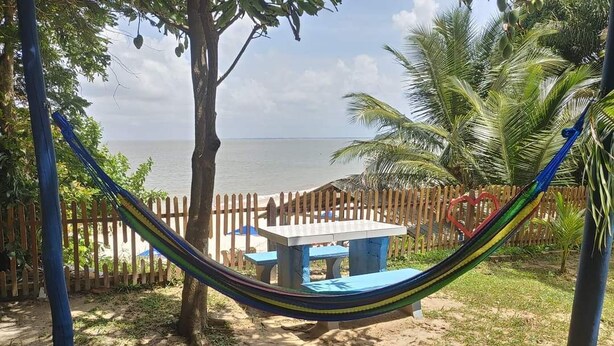 A hammock between trees, a wooden fence, and a view of the ocean. - My Stay  (Belo Horizonte)