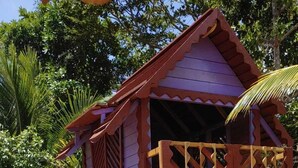 A wooden playhouse with a slide, set on sandy ground with trees in the background. - My Stay  (Belo Horizonte)