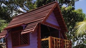 A wooden playhouse with a slide, built on stilts over sand, surrounded by trees and a fence. - My Stay  (Belo Horizonte)