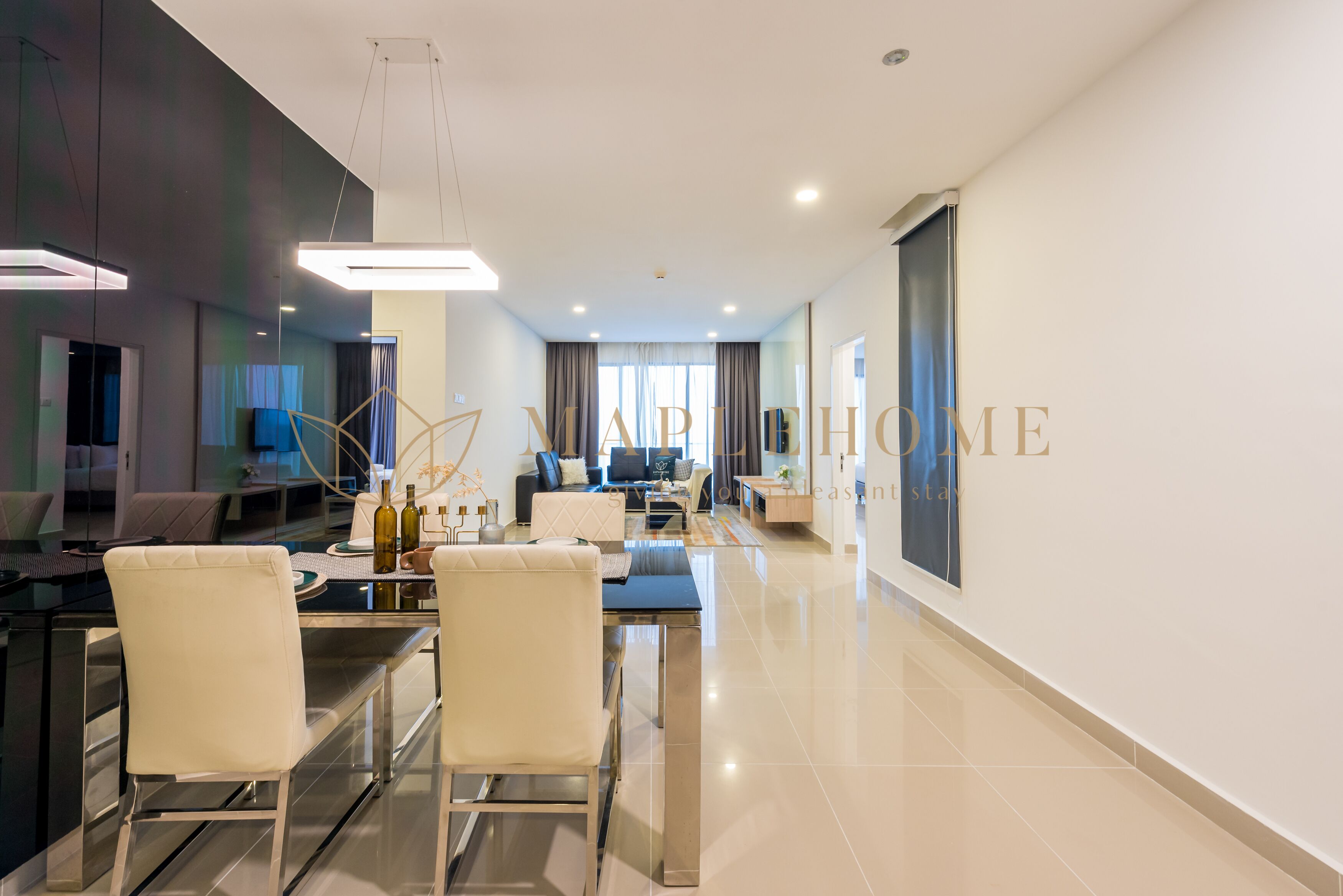 Quarto de hotel moderno com área de refeições, sala de estar e uma janela grande com cortinas.