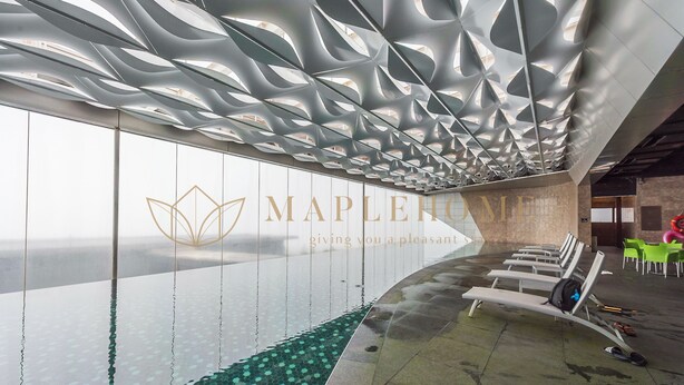 A modern hotel interior with a unique ceiling design, a wall with a logo, and a pool area. - Ion Delemon Premier Suites Genting (Genting Highlands)
