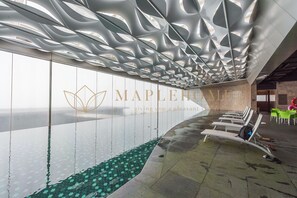 A modern hotel interior with a unique ceiling design, a wall with a logo, and a pool area. - Ion Delemon Premier Suites Genting (Genting Highlands)