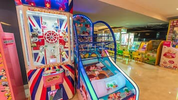 Un salón de juegos luminoso con diversas máquinas, incluyendo una máquina con pinzas y un juego de carreras.