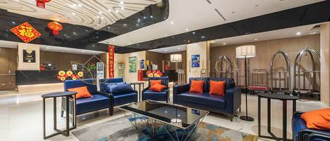 A modern hotel lobby with blue sofas, a glass coffee table, and red lanterns.
