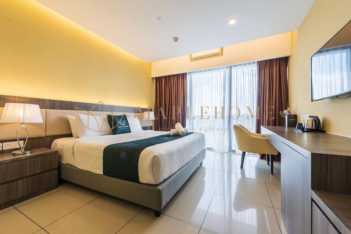 A hotel room with a bed, bedside tables, a desk, a chair, and a large window with curtains.
