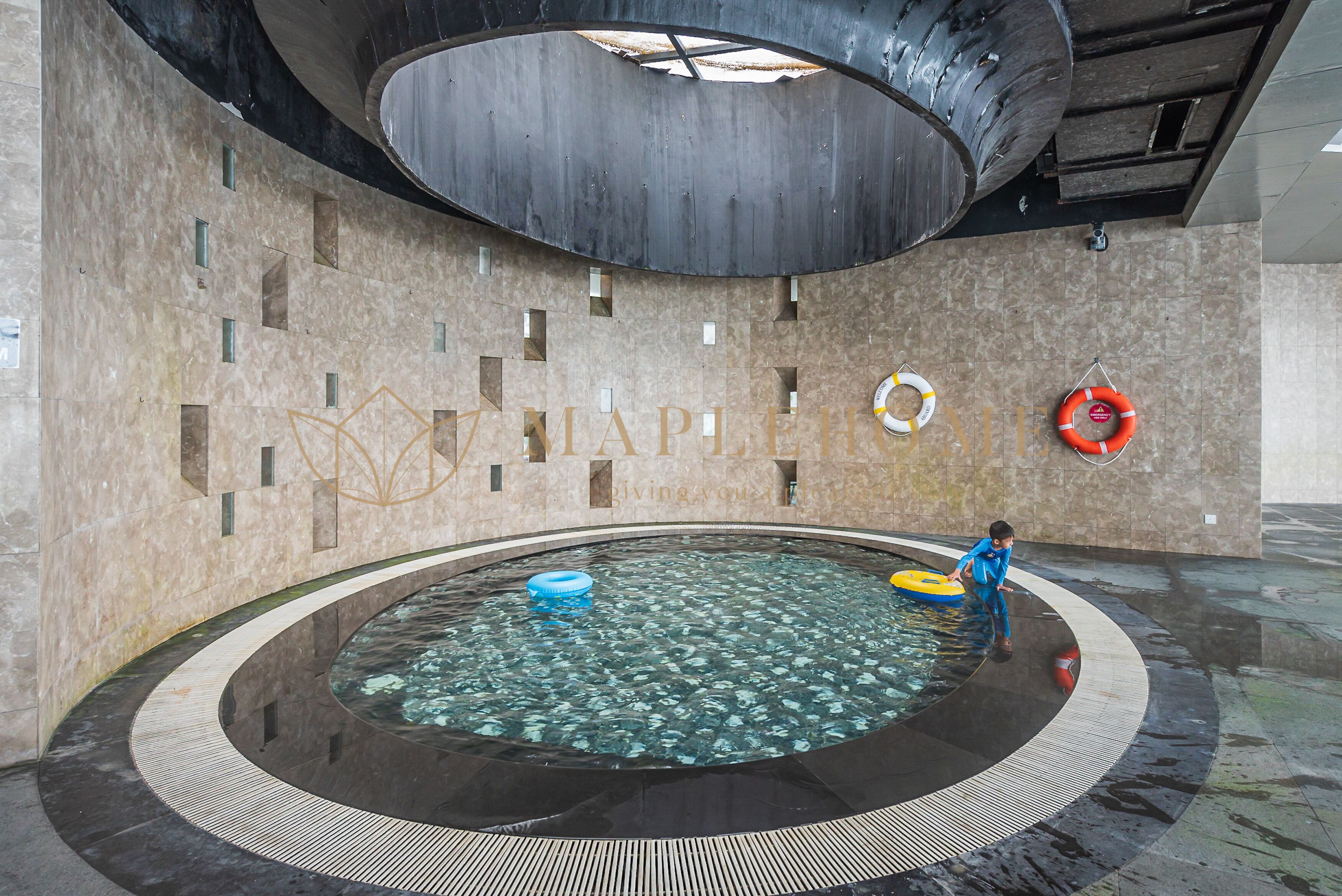 A modern indoor pool with a circular design, clear water, and safety equipment.