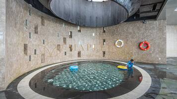 Una piscina interior moderna con diseño circular, agua cristalina y equipo de seguridad.