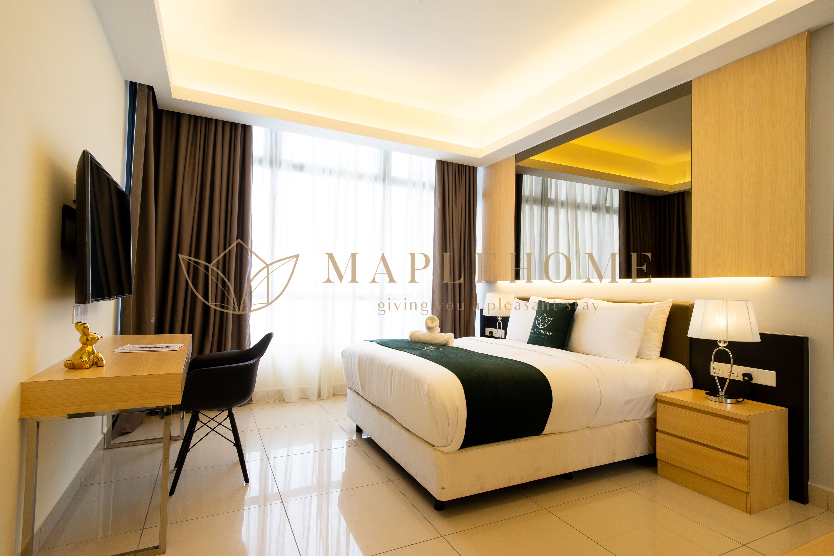 A hotel room with a bed, bedside table, lamp, desk with chair, and a television.