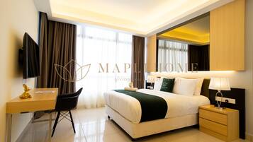 Una habitación de hotel con cama, mesita de noche, lámpara, escritorio con silla y televisor.