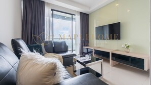 A modern living room with a black leather sofa, a glass coffee table, and a flat-screen TV mounted on the wall. - Ion Delemon Premier Suites Genting (Genting Highlands)