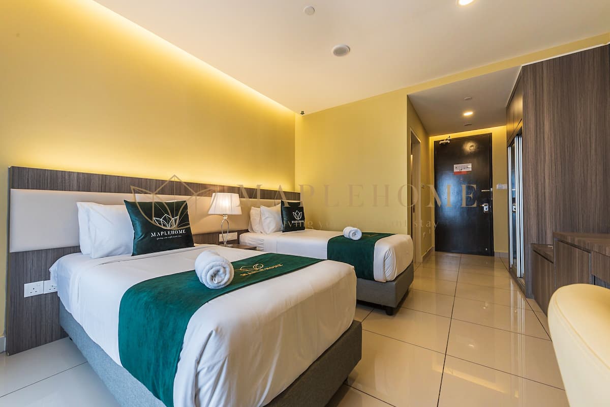 A hotel room with two beds, a bathroom, and a hallway.