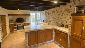 Una cocina con pared de piedra, armarios de madera y una isla grande.