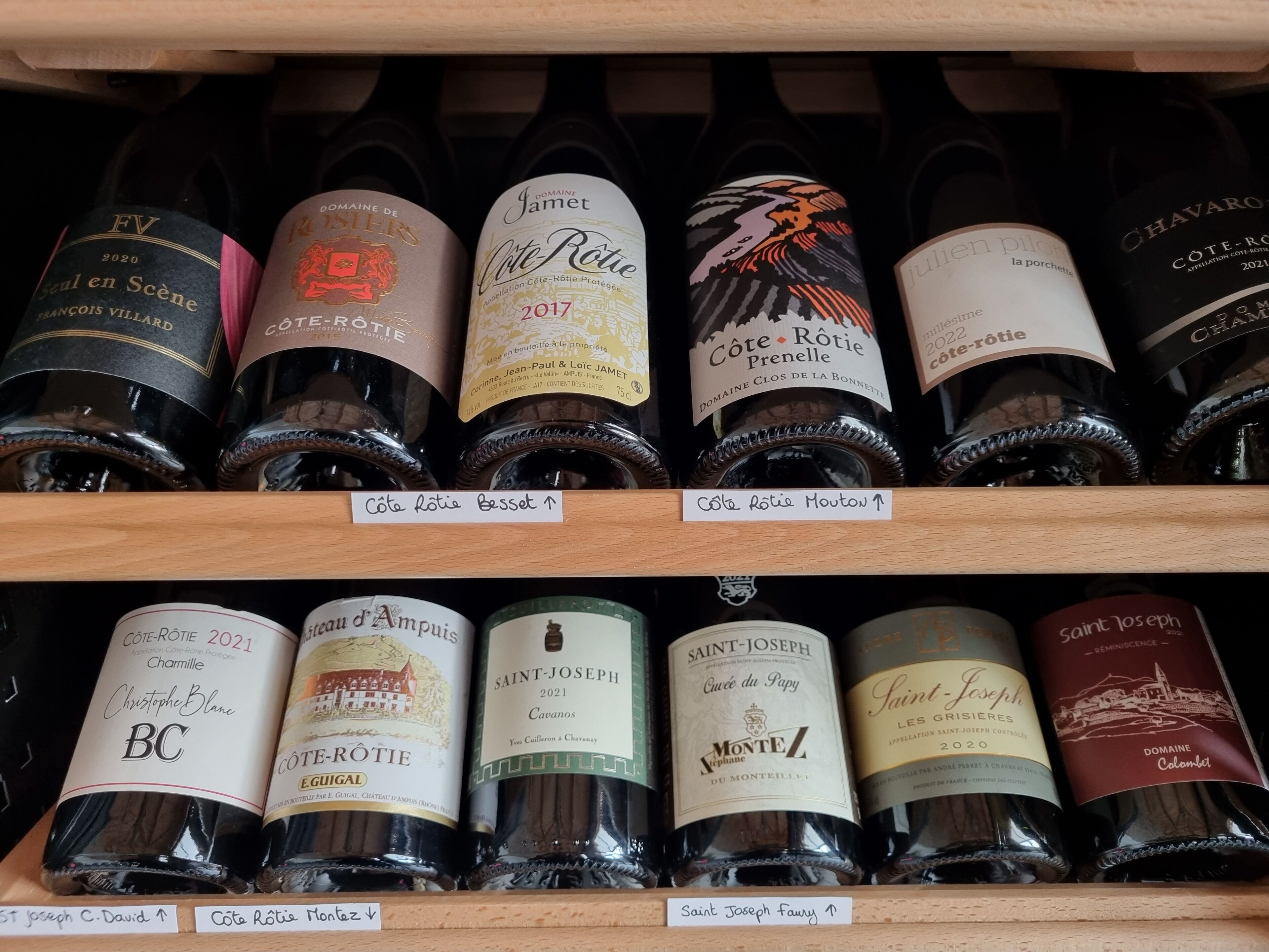 A wine rack with various bottles of Cote-Rotie wine from different years.