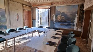 Un salón de conferencias con una larga mesa, sillas y un mural de un paisaje montañoso.